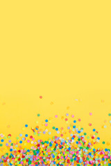 Round frame made of colored confetti. Yellow background. Festive confetti.