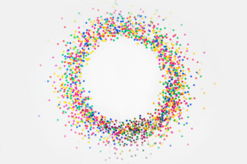 Round frame made of colored confetti stars. White background. Festive confetti.