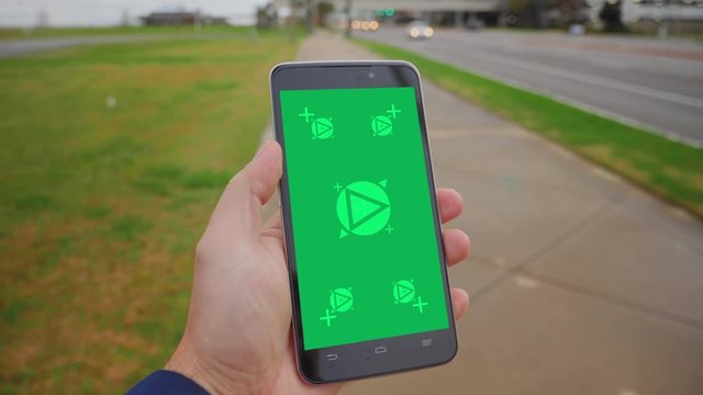 Holding a green screen smartphone while walking near Biloxi's Route 90 Beach Boulevard on an overcast day. Optional tracking points on screen for advanced screen replacement.  	