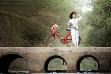 woman with Vietnam culture traditional dress, Ao dai and bicycle on the bridge