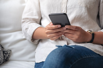 Closeup image of a woman holding , using and looking at smart phone in cafe