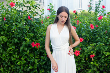girl in a white dress on a background of red tropical flowers