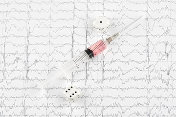 Syringe with medicine and dice on MRI cardiogram.
