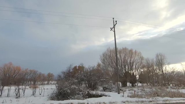 Drive Plate-POV-Passing snowy farms and fields at sundown on cloudy day