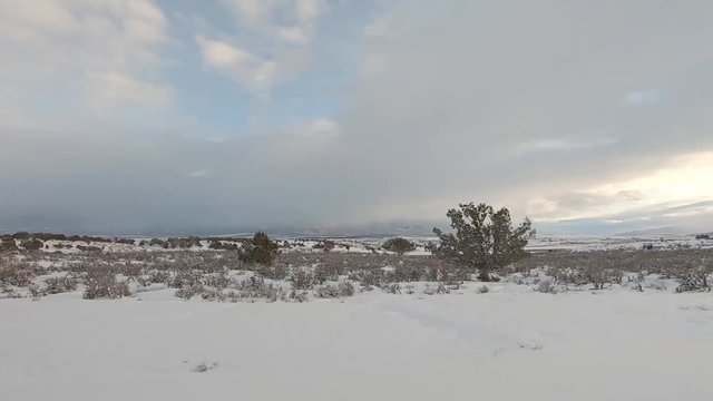 Drive Plate-POV-Side view passing snowy sage and juniper covered hills at sunset