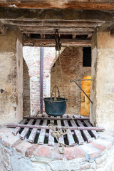 Old well with iron cauldron in medieval house in tuscany, Italy