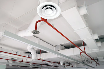 Perspective view of white air duct on the ceiling with red water sprinkler pipe - obrazy, fototapety, plakaty