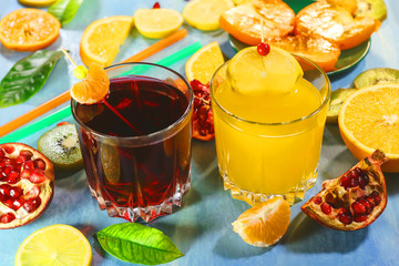 Pomegranate juice and orange juice. sliced ​​citrus fruits on a blue painted board. orange, kiwi, pomegranate, persimmon, mandarin. with fruit sticks.