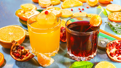Pomegranate juice and orange juice. sliced ​​citrus fruits on a blue painted board. orange, kiwi, pomegranate, persimmon, mandarin. with fruit sticks.