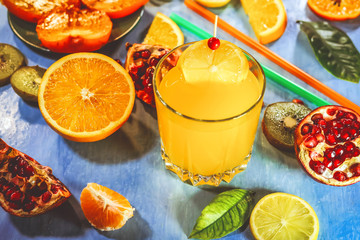 orange juice. sliced ​​citrus fruits on a blue painted board. orange, kiwi, pomegranate, persimmon, mandarin. with fruit sticks.