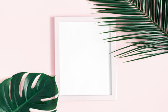 Summer composition. Tropical palm leaves, photo frame on pink background. Summer, nature concept. Flat lay, top view, copy space