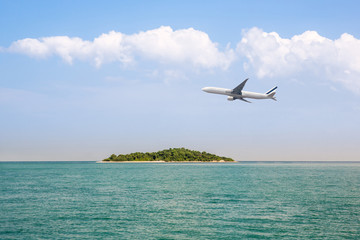 Fototapeta na wymiar passenger plane flying over beautiful blue ocean and island sea beach use for summer holiday vacation traveling . Airplane flying over amazing ocean landscape with tropical island.
