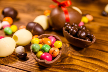 Chocolate easter eggs and multicolored candies on wooden table