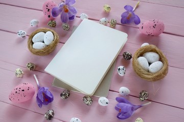 Easter Flat lay.  Easter Mockup.Decorative eggs, blank notepad and purple crocus flowers on a pink board wooden background