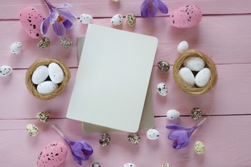 Fototapeta na wymiar Easter Flat lay. Spring Easter Mockup.Decorative eggs, blank notepad and purple crocus flowers on a pink board wooden background