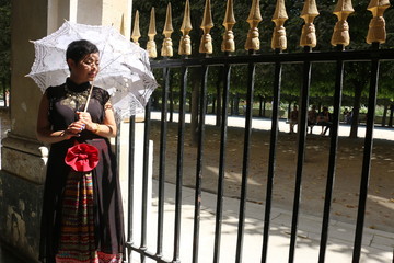 Femme et ombrelle blanche devant les grilles du palais royal à Paris