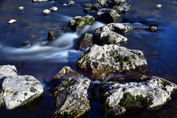 Steine im Fluss mit kleinen Wasserstrudeln