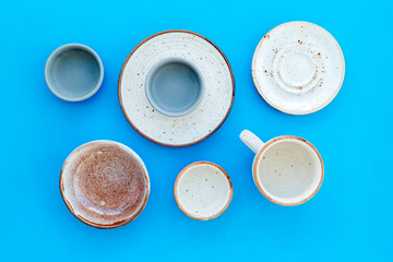 Kitchen concept. Crockery kit. Empty ceramic plates and mugs on blue background top view