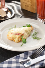 Chicken breast fillet baked with Parmesan cheese, tomato and herbs with glass of tomato juice on the table