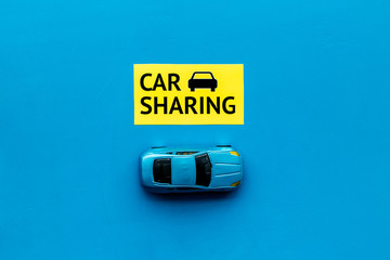 Carsharing concept. Toy car near text car sharing on blue background top view copy space