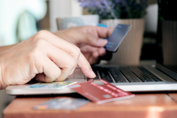 Shot of man hand typing on laptop and holding credit card, online transactions concept.