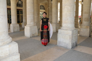 Femme avec ombrelle blanche marchant sous les arcades du palais royal à Paris
