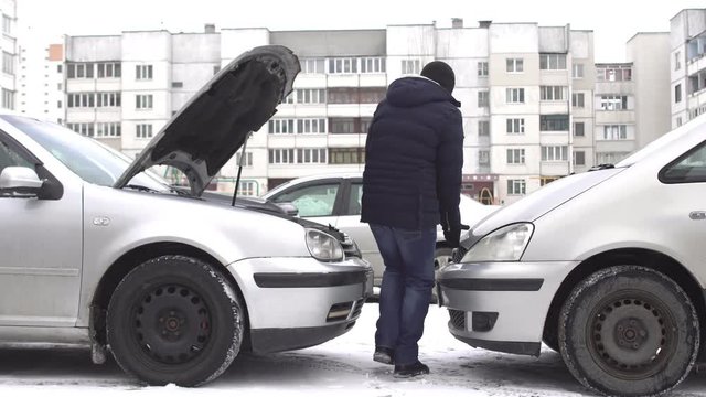 A man prepares a car donor to start a car with a discharged battery in winter, jump start, accumulator