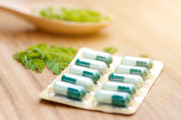 Fototapeta na wymiar herbal capsules from herb on wooden table 
