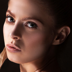 Fototapeta premium Girl beauty face close-up with clean skin, natural make-up, clean fresh skin, dark shadow portrait