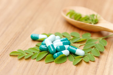 Fototapeta na wymiar herbal capsules from herb on wooden table 