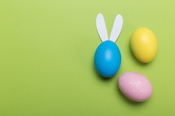 Colorfull easter eggs in nest on green pastel color background with space.