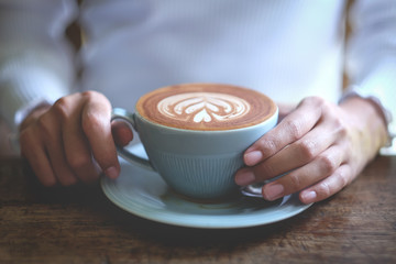 hand touching latte art coffee in cafe 