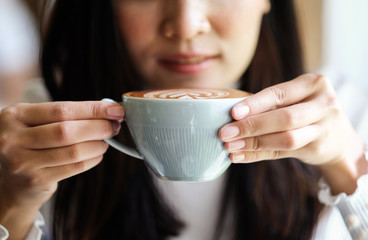 girl hand holding latte coffee in relaxing time of cafe 