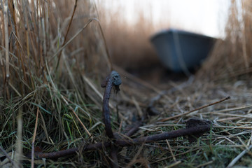 Symbolfoto, Anker mit unscharfen Fischerboot im Hintergrund