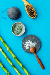 Hair care, hair spa. Cosmetics based on bamboo charcoal powder near comb on blue background top view