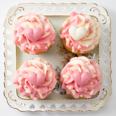 Four pink cream muffins on a white plate on a plate.
