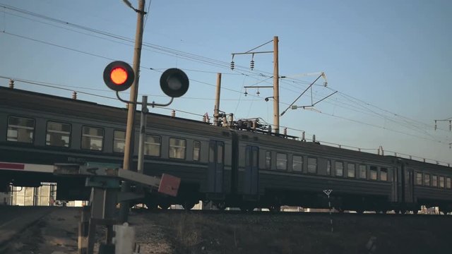 the train passes by a railway crossing, a barrier and a red semaphore