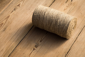 A roll of twine on a wooden background. Selelective focus. Close-up. Free space for text.