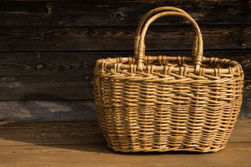 Fototapeta na wymiar Ancient wicker basket on a wooden background. Selective focus. Free space for text.