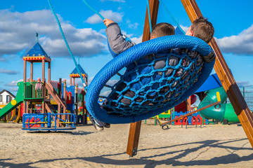Swings on modern kids playground. Children have fun on the cool swing