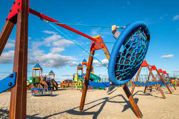 Swings on modern kids playground. Children have fun on the cool swing