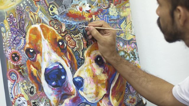 Artist painting his art work, acrylic color on canvas, about his beagle dogs and himself on earth with beautiful and colorful pattern