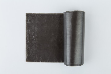 Black plastic polyethylene garbage bags roll isolated over the white background.