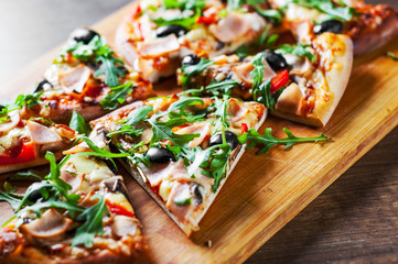 Pizza with Mozzarella cheese, mushrooms, ham, tomato sauce, pepper, olives, Spices and Fresh arugula. Italian pizza on wooden table background