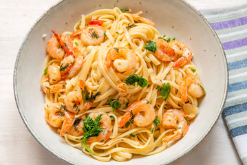 Linguine with shrimps on a rustic plate close-up, top view - traditional Mediterranean pasta with seafood, Italian cuisine..