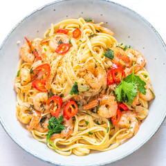 Linguine with shrimps on a rustic plate close-up, top view - traditional Mediterranean pasta with seafood, Italian cuisine..