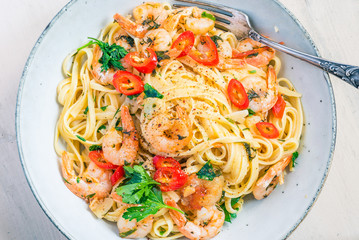 Linguine with shrimps on a rustic plate close-up, top view - traditional Mediterranean pasta with seafood, Italian cuisine..