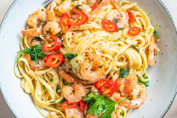 Linguine with shrimps on a rustic plate close-up, top view - traditional Mediterranean pasta with seafood, Italian cuisine..