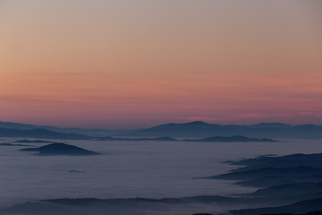 Fototapeta na wymiar Beautifully colored sky at dusk, with mountains layers over a sea of fog
