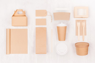 Blank different cardboard packaging for fast food - coffee cup, notebook, cutlery, sugar, spice, container and box for soup, sushi, burger on white wood board.